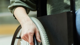 Close-up of young woman sitting in wheelchair and holding the wheel