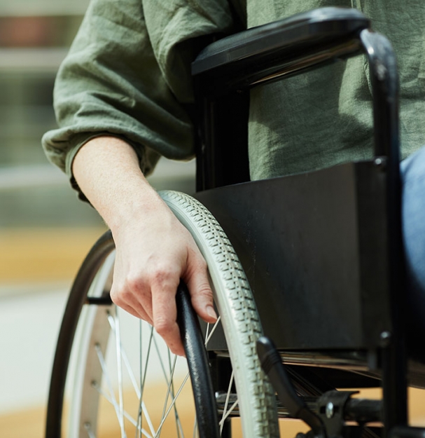 Close-up of young woman sitting in wheelchair and holding the wheel